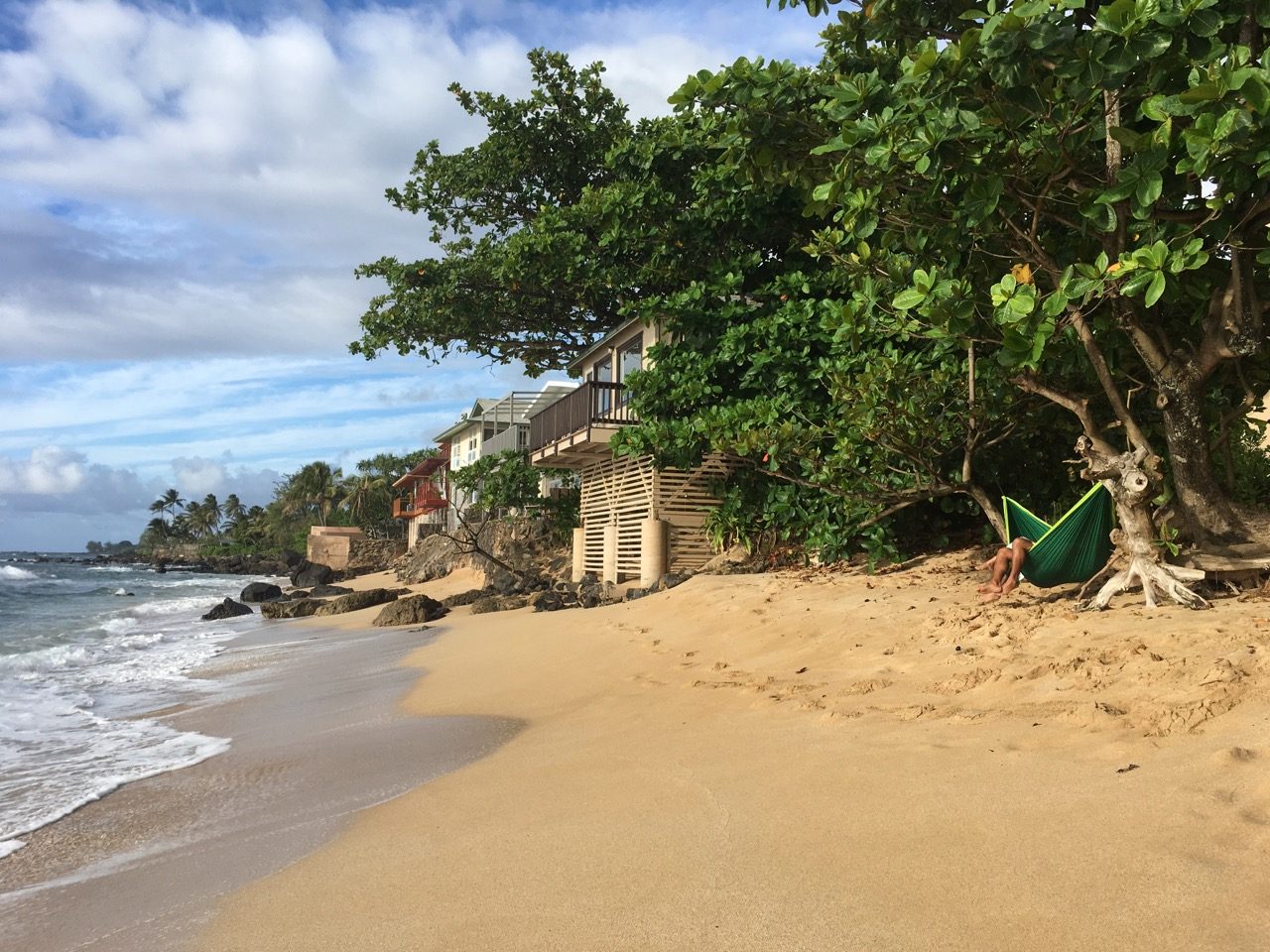A couple enjoys the late afternoon in a hammock on the beach in Oahu, Haleiwa